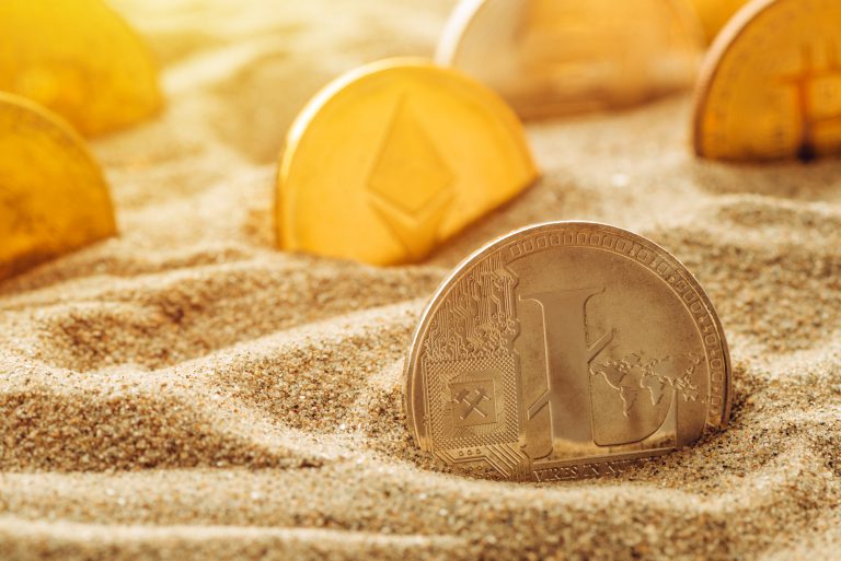 Silver Litecoin coin in sand
